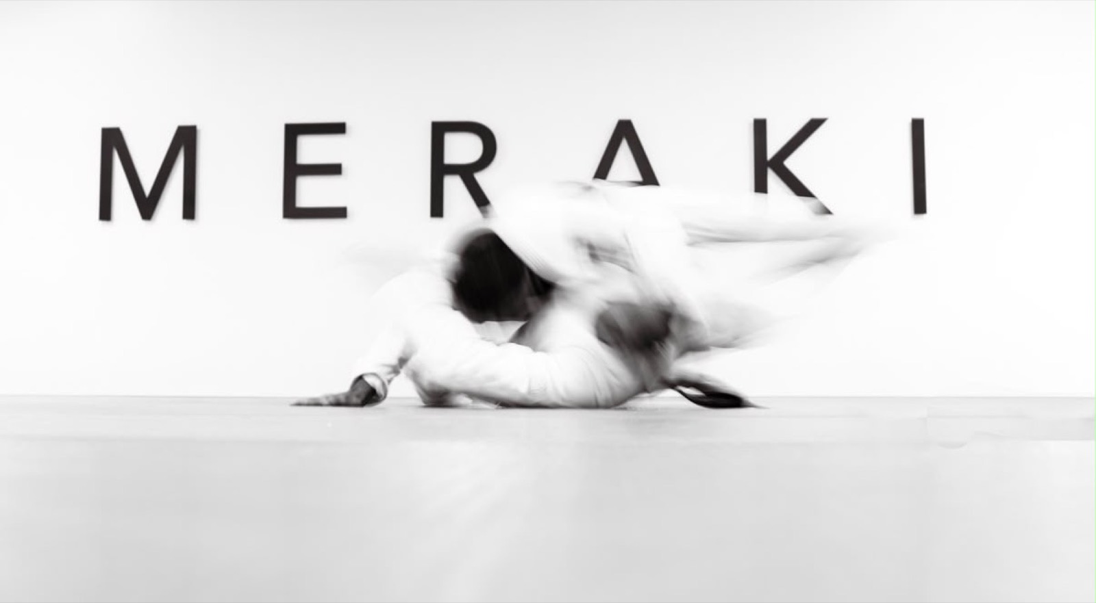 Two members mid-throw in front of the Meraki wall